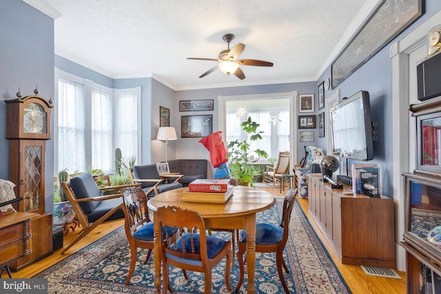 dining area featuring visible vents, crown molding, light wood finished floors, and ceiling fan