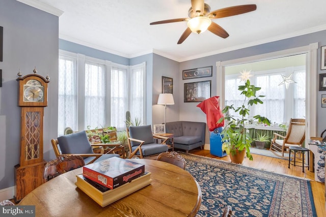 living area featuring crown molding, plenty of natural light, baseboards, and wood finished floors