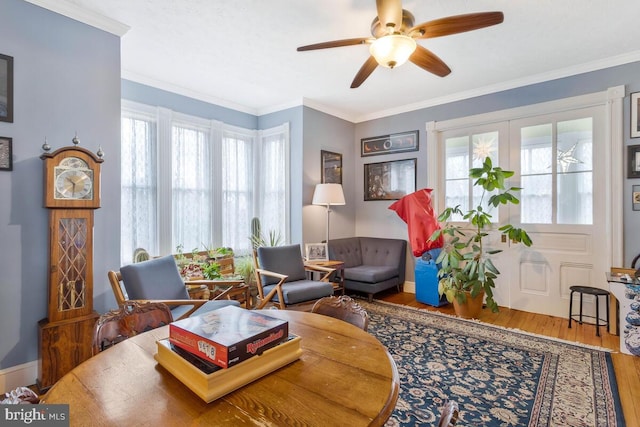 living area featuring ceiling fan, baseboards, wood finished floors, and crown molding