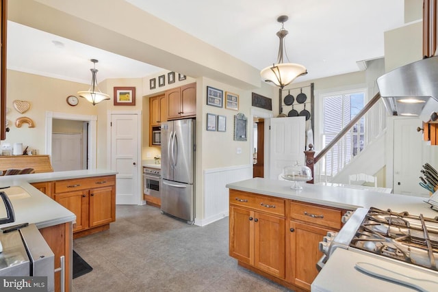 kitchen featuring stainless steel appliances, a wainscoted wall, light countertops, and a peninsula