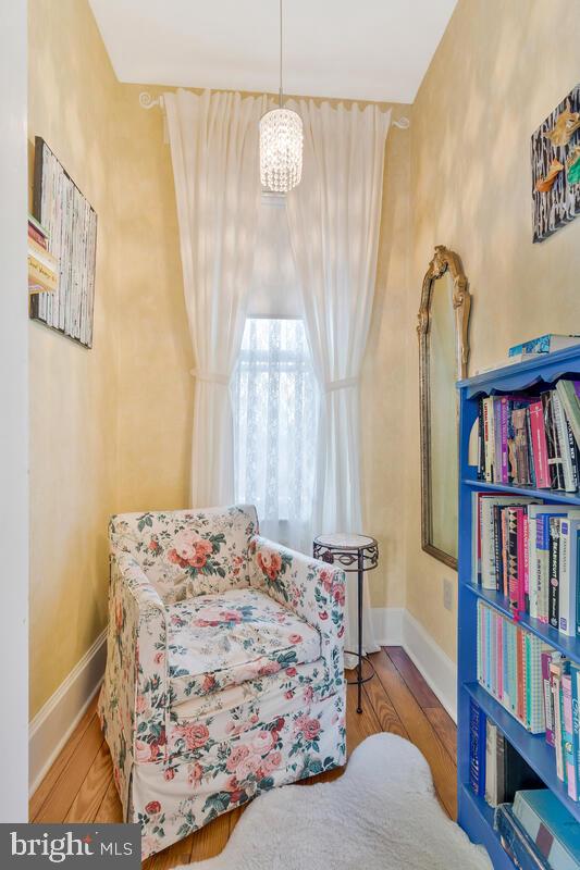 sitting room with a notable chandelier, baseboards, and wood finished floors