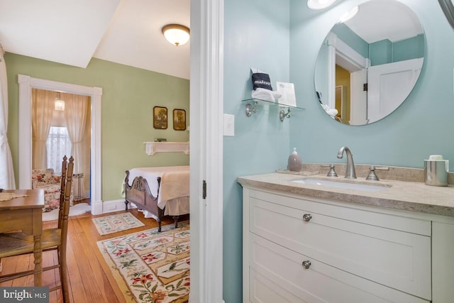 ensuite bathroom featuring baseboards, ensuite bathroom, wood finished floors, and vanity