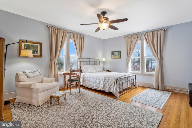 bedroom featuring light wood finished floors, multiple windows, and baseboards