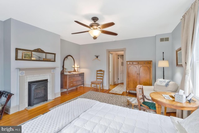 bedroom with baseboards, wood finished floors, visible vents, and a ceiling fan