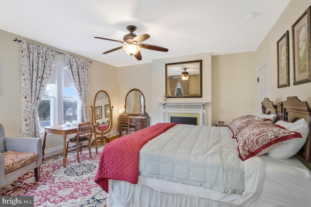 bedroom featuring ceiling fan, a fireplace, and baseboards