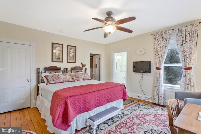 bedroom with ensuite bath, ceiling fan, baseboards, and wood finished floors