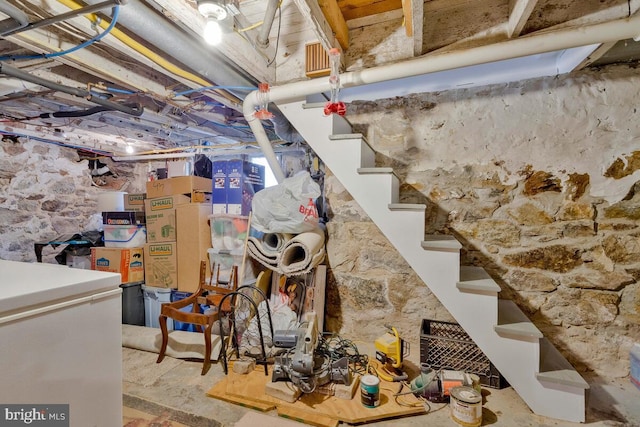 unfinished below grade area with stairway and white fridge