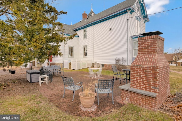 rear view of house featuring a patio, outdoor dining area, and a chimney