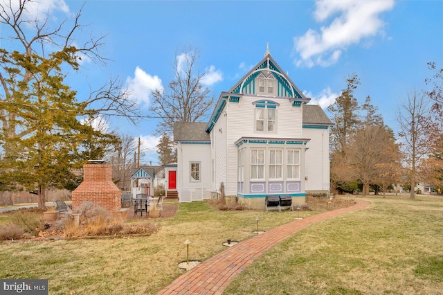 rear view of property featuring a fireplace and a yard