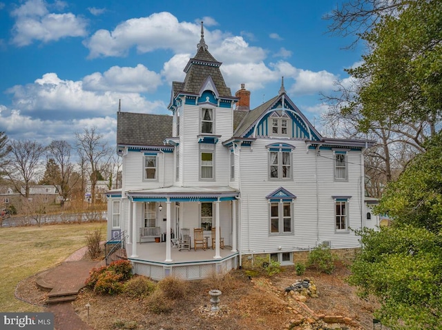 back of property with a chimney and a lawn