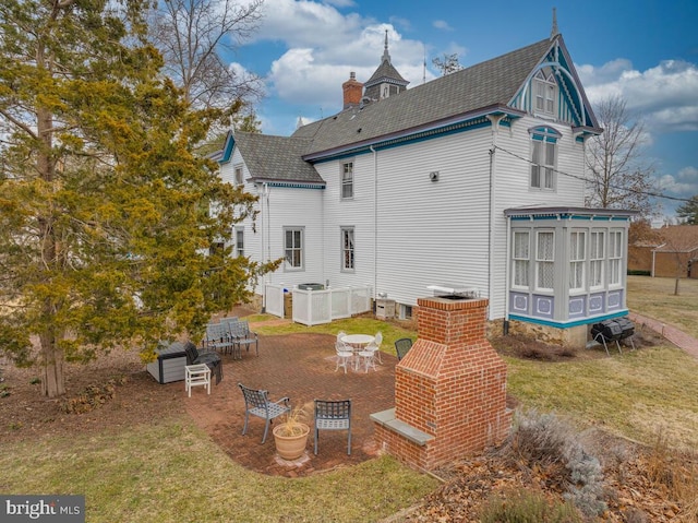 rear view of house featuring central AC unit, a chimney, outdoor dining area, a yard, and a patio area