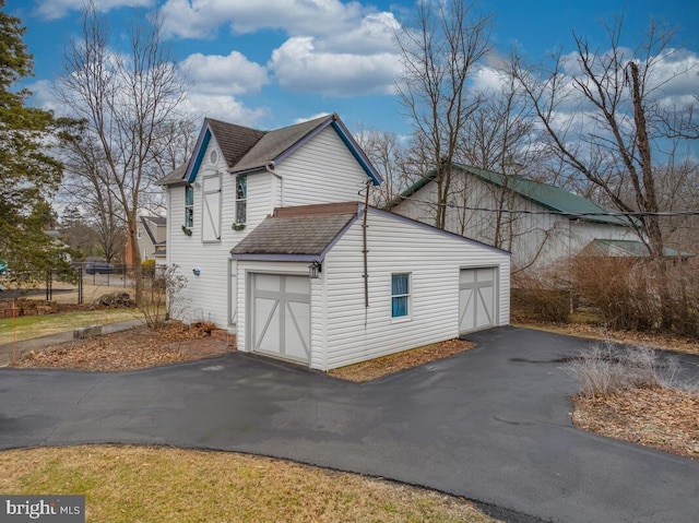 view of home's exterior with a shingled roof and a detached garage