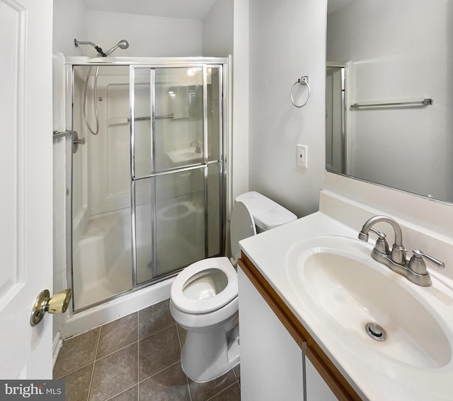 bathroom with a shower with shower door, vanity, tile patterned flooring, and toilet