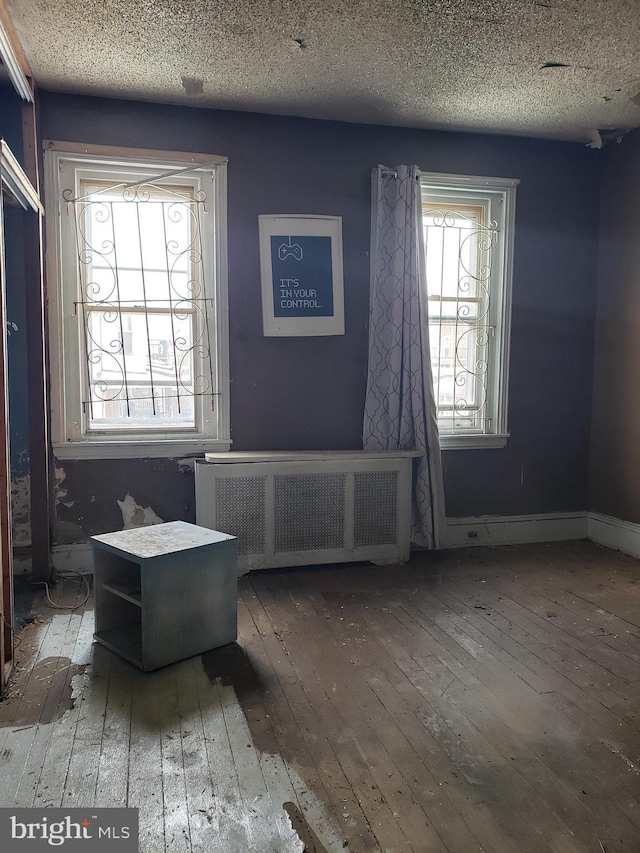 interior space with a textured ceiling, dark hardwood / wood-style floors, and radiator