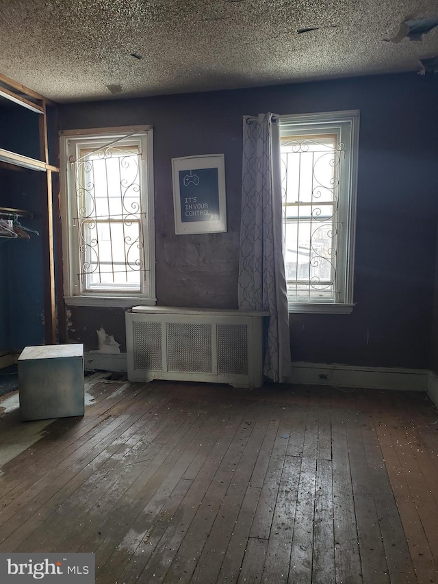 interior space featuring wood-type flooring, a textured ceiling, and radiator