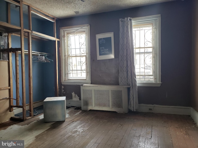 miscellaneous room featuring radiator, hardwood / wood-style floors, and a textured ceiling