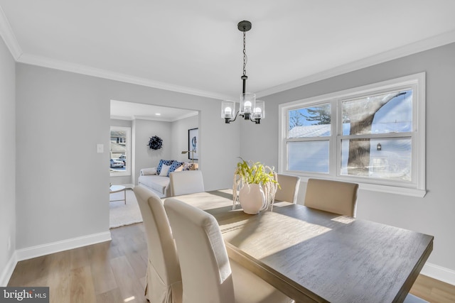 dining space featuring a chandelier, wood-type flooring, a wealth of natural light, and ornamental molding