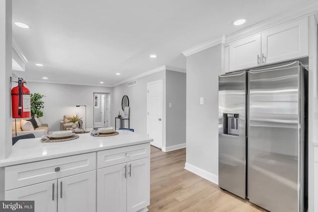 kitchen with light hardwood / wood-style floors, stainless steel fridge, white cabinetry, and ornamental molding