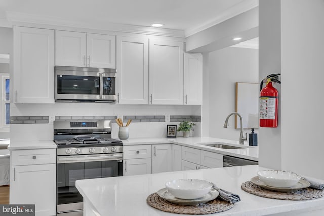 kitchen featuring appliances with stainless steel finishes, white cabinetry, sink, backsplash, and kitchen peninsula