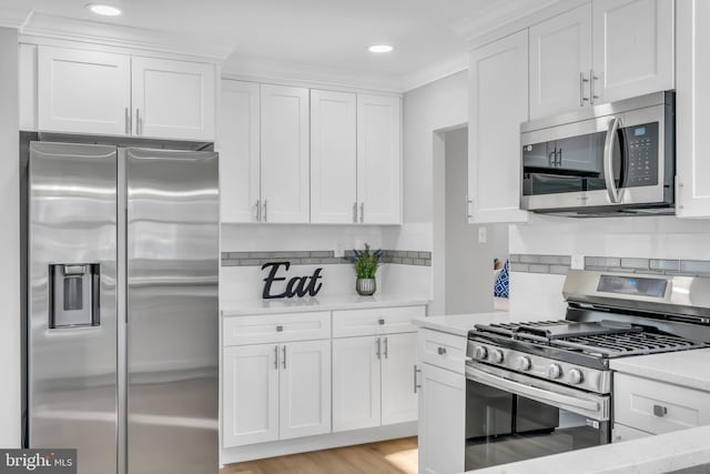 kitchen with light stone counters, crown molding, white cabinets, and stainless steel appliances