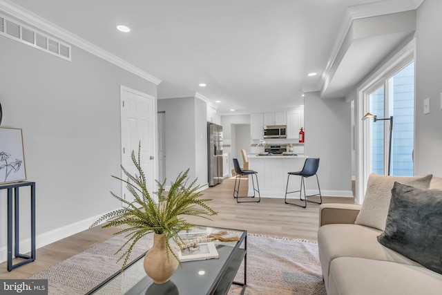 living room with light wood-type flooring and ornamental molding