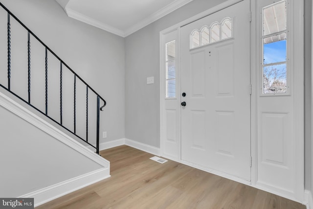 foyer entrance with light hardwood / wood-style flooring and ornamental molding