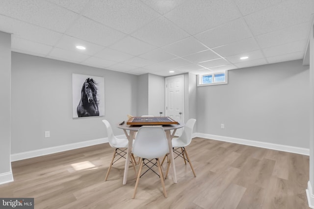 dining space with a paneled ceiling and light wood-type flooring