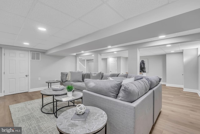 living room featuring light wood-type flooring and a drop ceiling