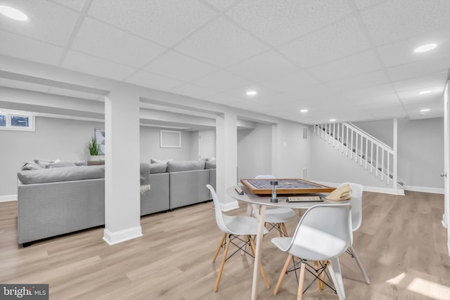 dining space with a drop ceiling and light hardwood / wood-style flooring