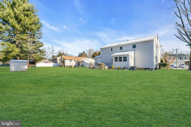 rear view of house featuring a wooden deck, a lawn, and central air condition unit