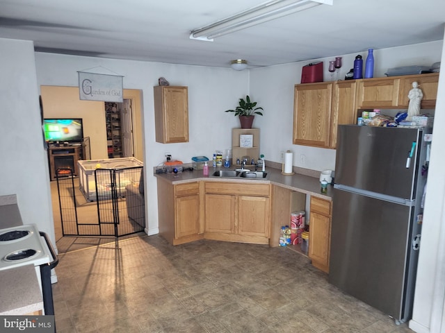 kitchen featuring stove, sink, and stainless steel refrigerator