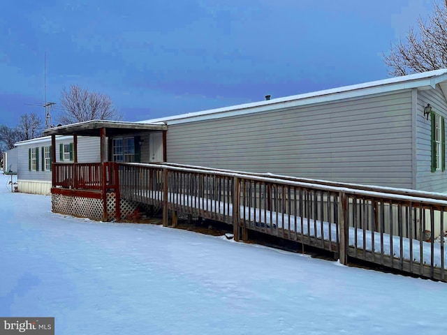 snow covered back of property with a deck