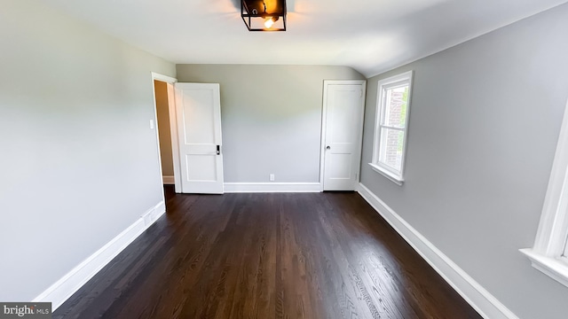 empty room with dark hardwood / wood-style floors and lofted ceiling