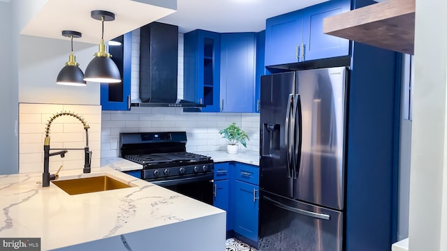 kitchen with range with gas stovetop, stainless steel refrigerator with ice dispenser, wall chimney range hood, sink, and light stone counters