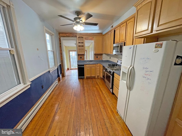 kitchen with appliances with stainless steel finishes, a baseboard heating unit, light wood-type flooring, sink, and ceiling fan