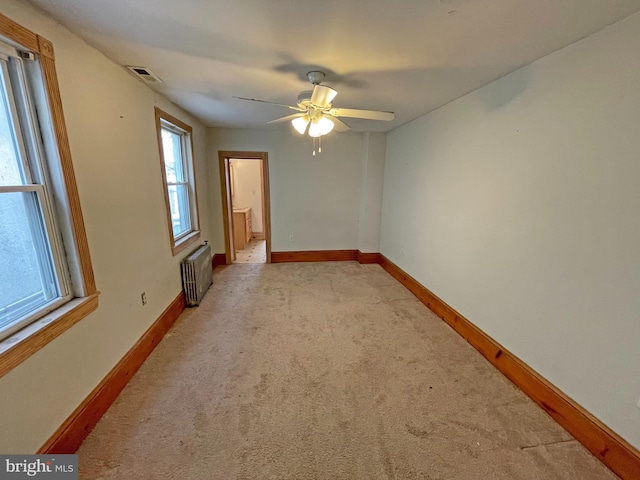 carpeted spare room with ceiling fan and radiator