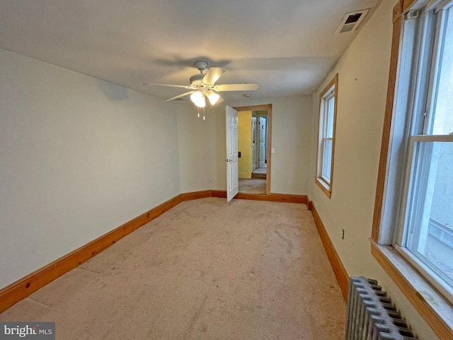 carpeted empty room featuring radiator and ceiling fan