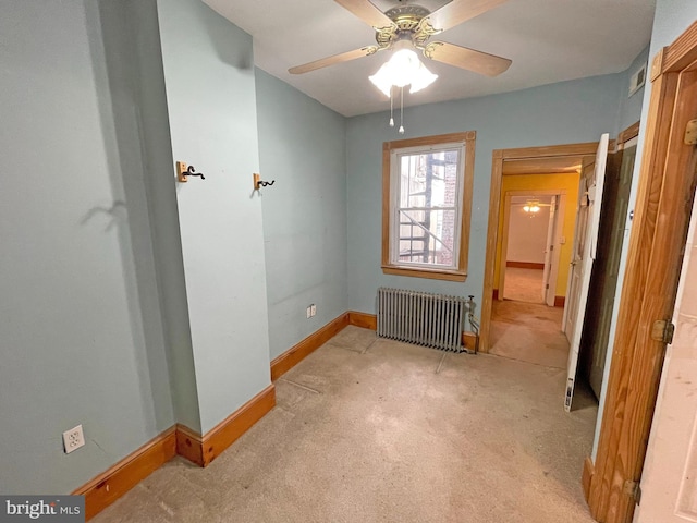 carpeted empty room with ceiling fan and radiator heating unit