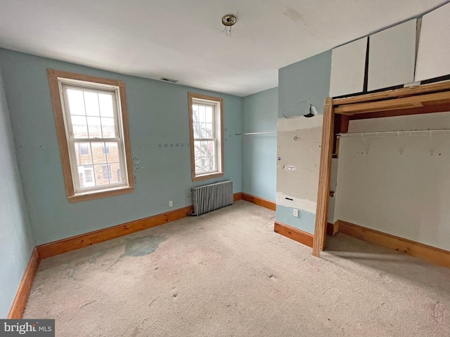 unfurnished bedroom featuring a closet, radiator heating unit, and light carpet