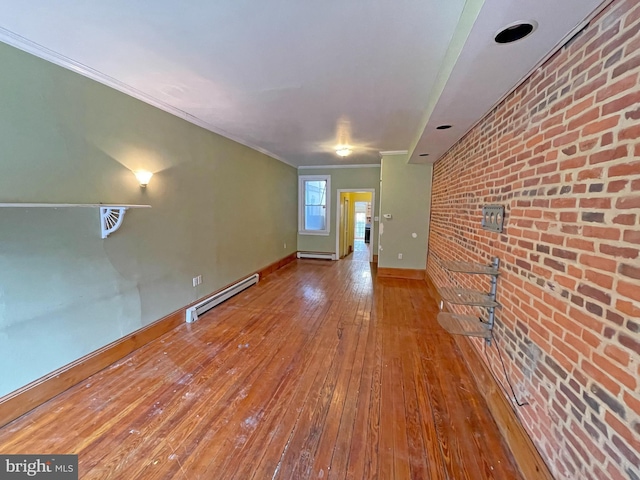 spare room featuring crown molding, hardwood / wood-style flooring, brick wall, and a baseboard heating unit