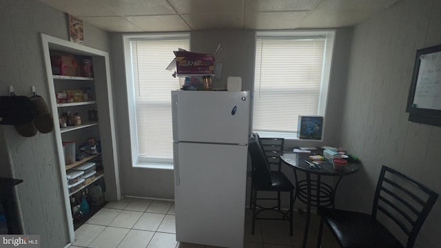 kitchen featuring a drop ceiling, light tile patterned floors, and white fridge