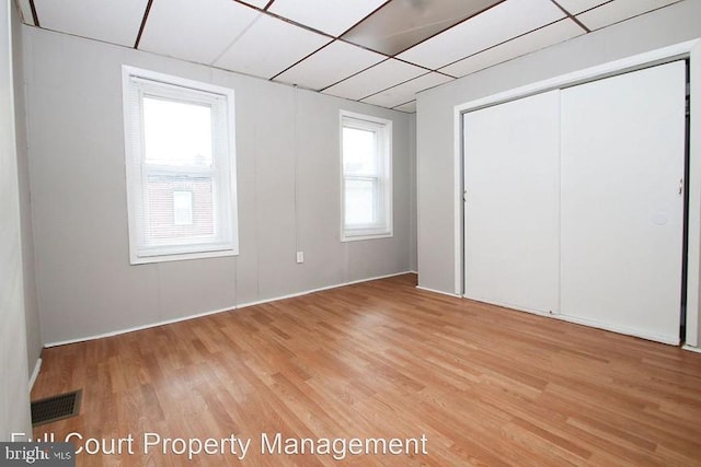 unfurnished bedroom featuring a closet, a paneled ceiling, and hardwood / wood-style floors