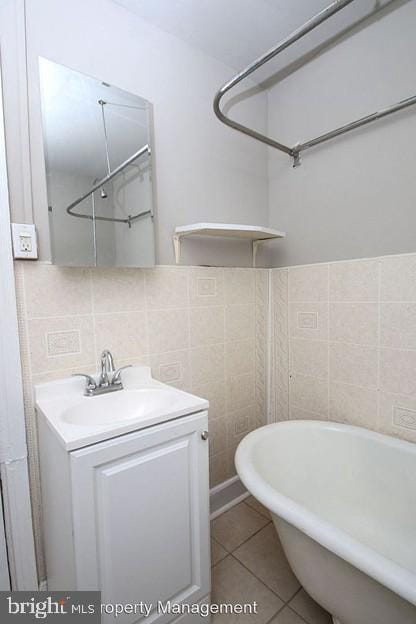 bathroom featuring tile patterned flooring, tile walls, a bathtub, vanity, and decorative backsplash