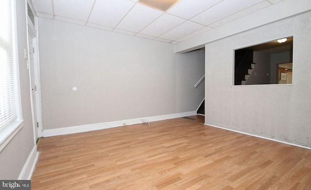 empty room with light hardwood / wood-style flooring and a paneled ceiling