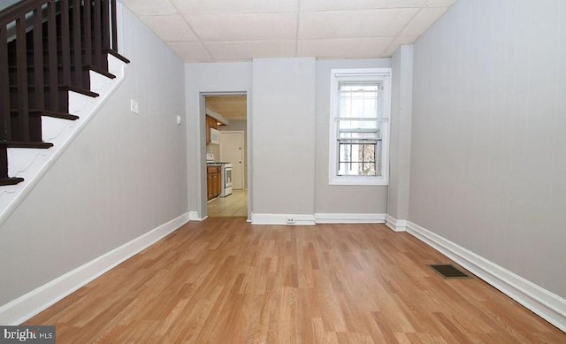 spare room with a paneled ceiling and light hardwood / wood-style flooring