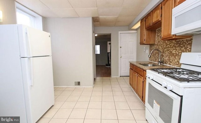 kitchen with sink, tasteful backsplash, light tile patterned floors, white appliances, and a drop ceiling