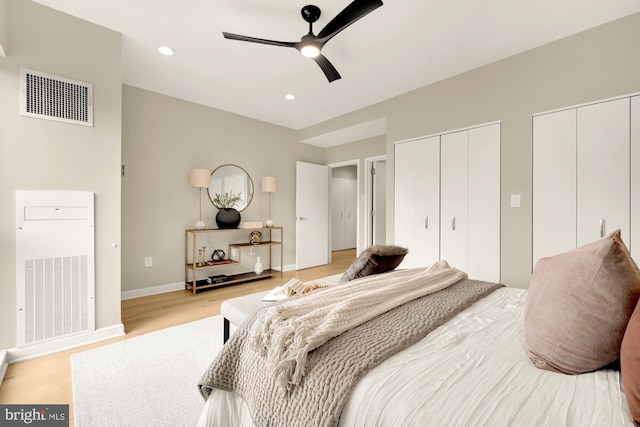 bedroom with multiple closets, ceiling fan, and light hardwood / wood-style floors