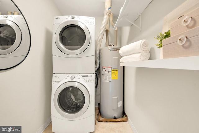 clothes washing area with electric water heater and stacked washer and clothes dryer