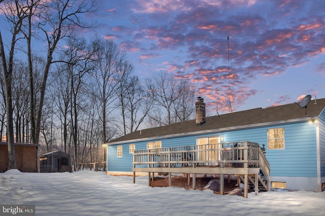 snow covered rear of property with a wooden deck