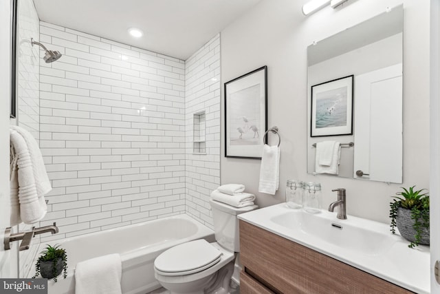 full bathroom featuring vanity, tiled shower / bath, and toilet